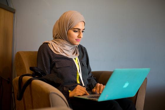 Photo of a young hijabi student working at her laptop in Cafe Rachel