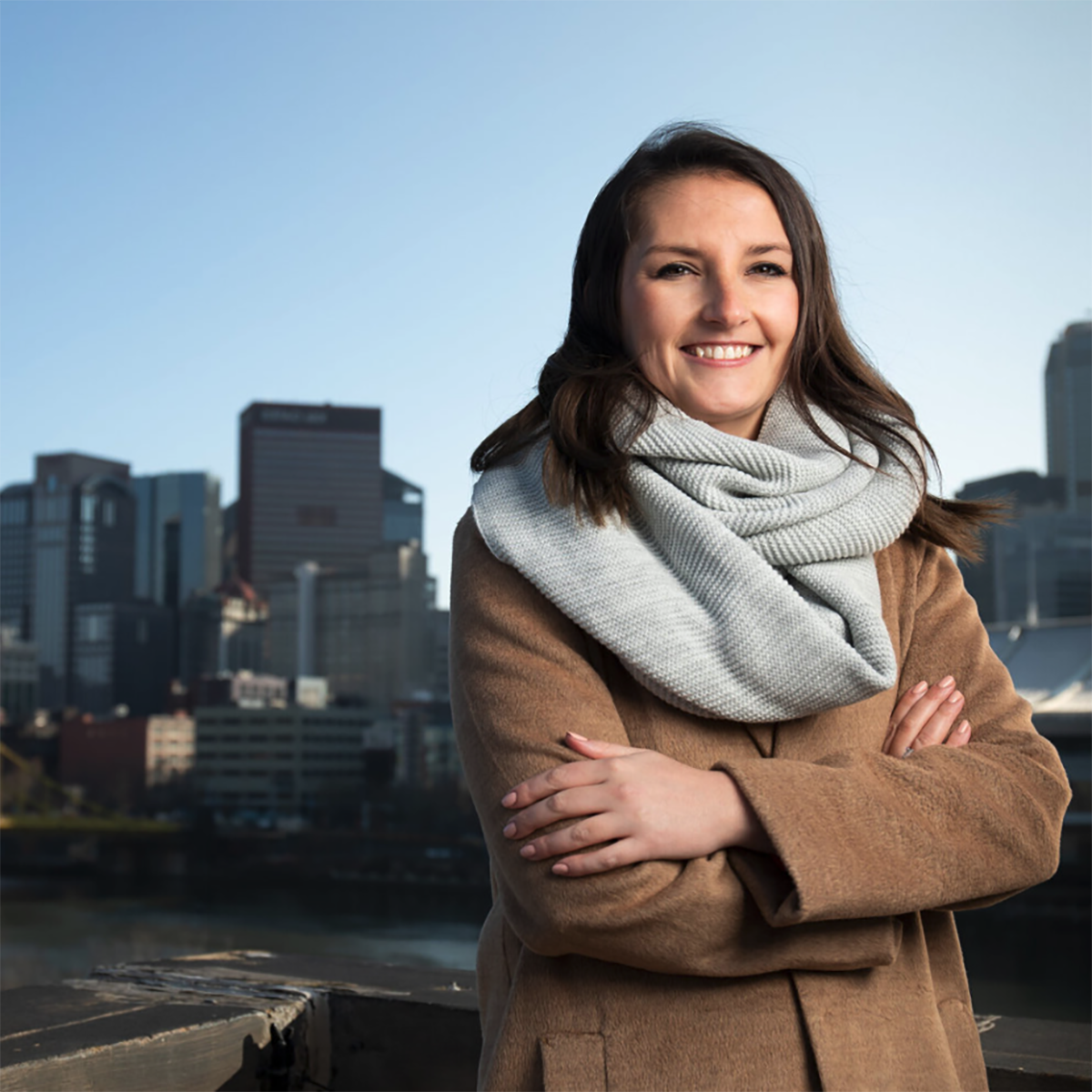 Photo of Caitlin Fadgen, smiling in front of the Pittsburgh skyline