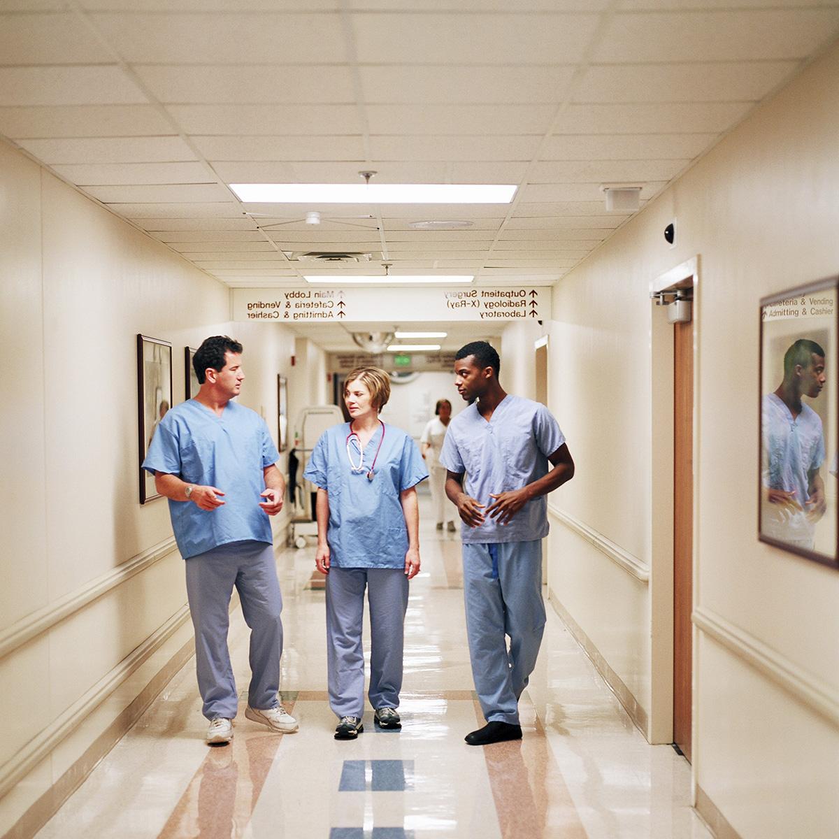 Photo of three nurses in scrubs walking down a hospital corridor