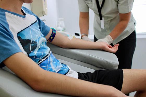 Photo of a boy in a blue t-shirt getting blood drawn by nurse. 