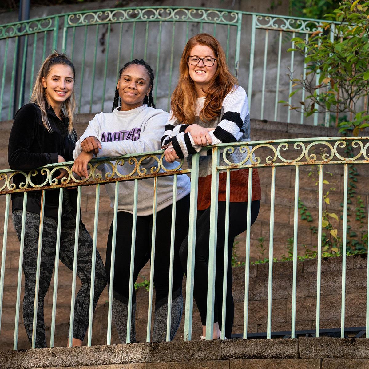 Photo of three Chatham University ELOTD students posing in front of gate