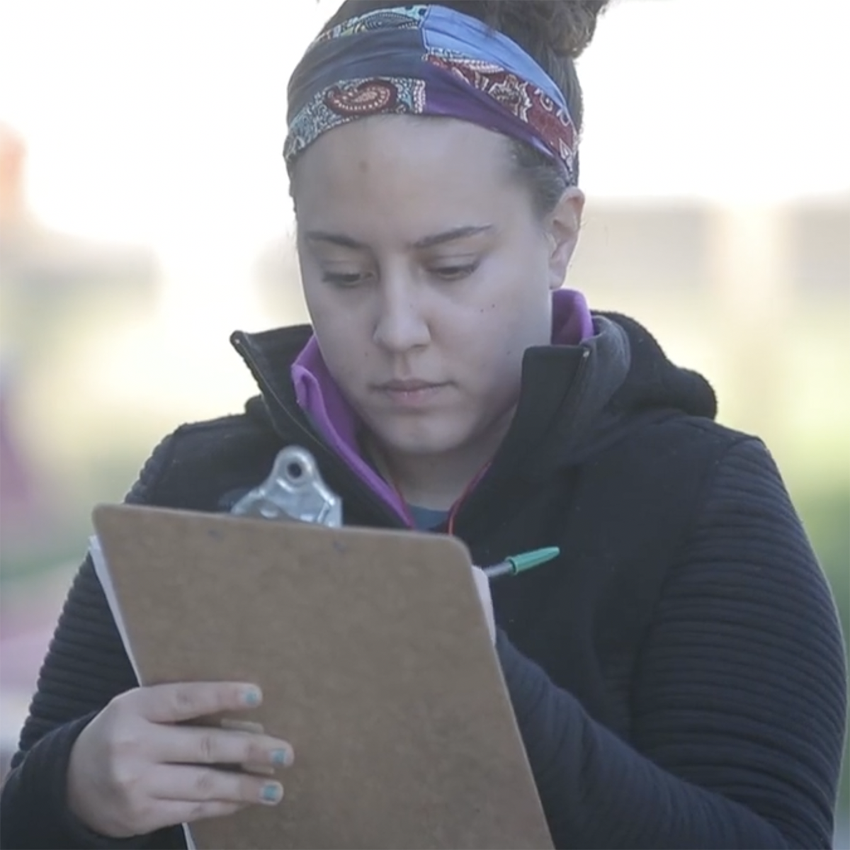 Photo of a young woman writing on a clipboard
