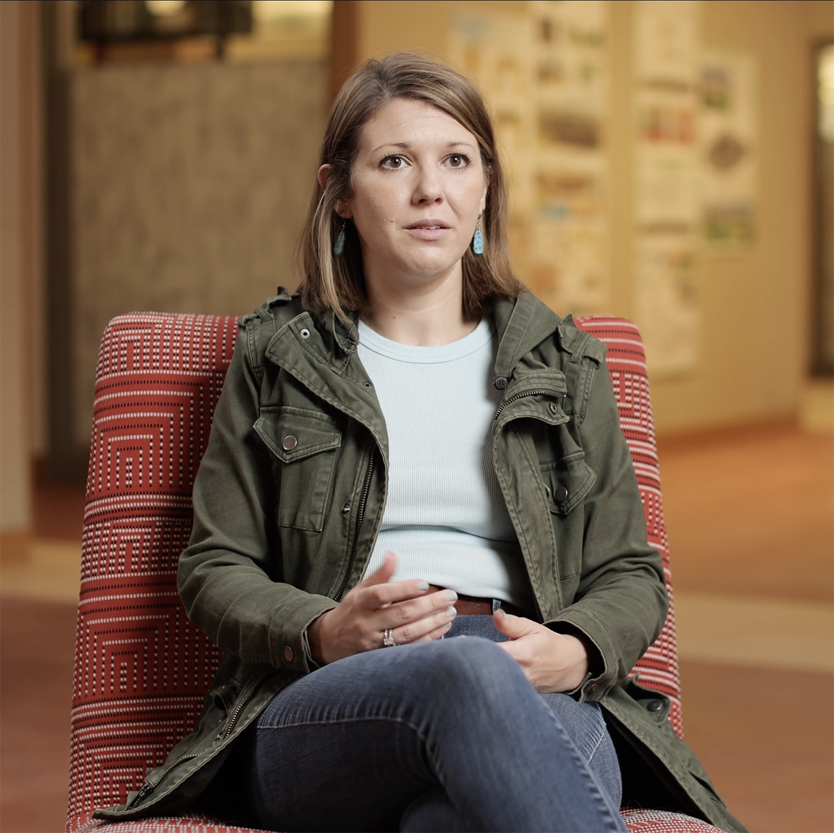 一位女校友坐在红椅子上接受视频采访的照片