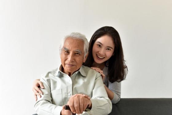 Photo of a young woman and an old man posing together and smiling