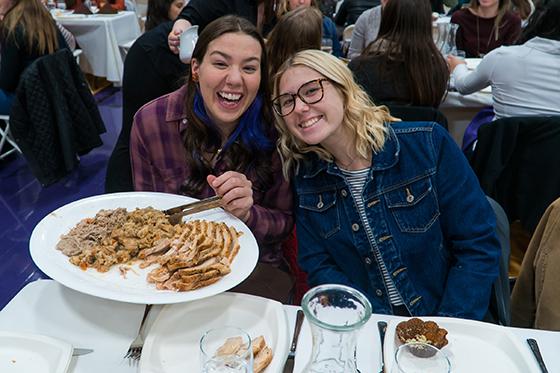 Photo of Chatham University students at Harvest Dinner holding a plate of turkey and stuffing. 